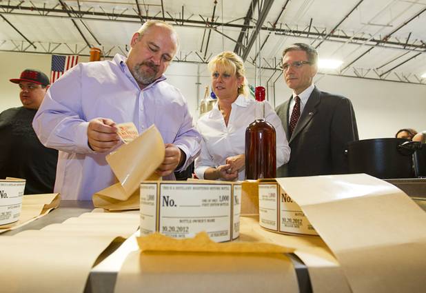 Las Vegas Distillery founder George Racz, left, helps Lisa Heck and her husband Congressman Joe Heck (R-NV) label a Nevada Whiskey bottle during the Historic First Edition Day at the Las Vegas Distillery in Henderson Saturday, November 17, 2012. The event marks the first bottling of several new spirits and the grand opening of the Booze Brothers Beverages distribution company and the Half Full Artisan Shop at the Distillery, a retail store. The spirits include Nevada vodka, whiskey, gin, rum and moonshine.