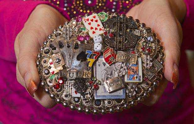 Sales associate Dawn North displays a gambling-themed ladies belt buckle at the Pinto Ranch western wear store in the Fashion Show Mall Monday, November 19, 2012. The buckle is made by artist Pam Wood in Yoakum, Texas.