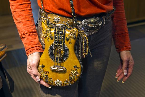 Connie Smith, a ladies department manager, models a guitar-shaped leather handbag at the Pinto Ranch western wear store in the Fashion Show Mall Monday, November 19, 2012.