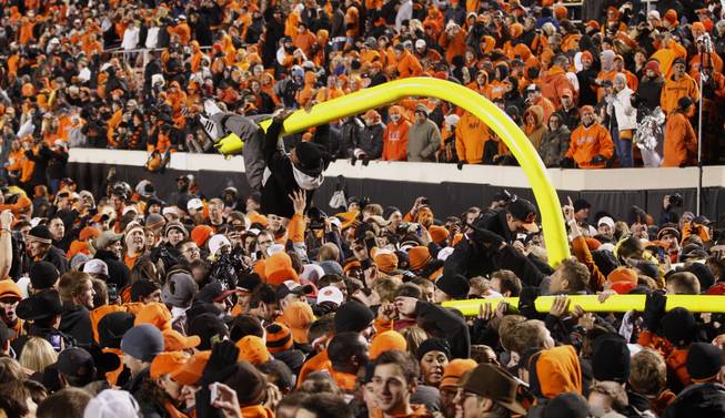 A fan hangs from a goal post after it was torn down in celebration of Oklahoma State's 44-10 win over Oklahoma in an NCAA college football game in Stillwater, Okla., Saturday, Dec. 3, 2011.