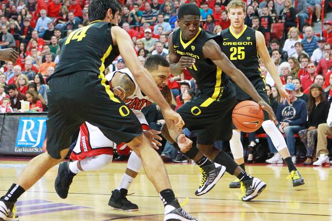 UNLV guard Anthony Marshall looses the ball while driving to the basket between Oregon's Arsalan Kazemi, left, and Damyean Dotson during their game Friday, Nov. 23, 2012 in the Global Sports Classic. Oregon upset the 18th-ranked Rebels 83-79.