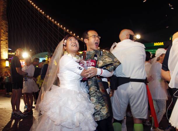 Akiko Hashimoto, left, and Toshihide Miyake celebrate after getting married in front of New York-New York during the Zappos.com Rock 'n' Roll Las Vegas Marathon Sunday, Dec. 2, 2012.