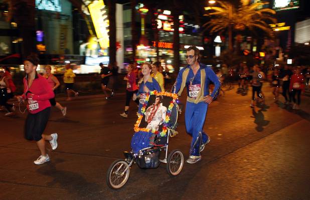 A couple dressed as Elvis Presley run northbound on the Las vegas Strip during the Zappos.com Rock 'n' Roll Las Vegas Marathon Sunday, Dec. 2, 2012.