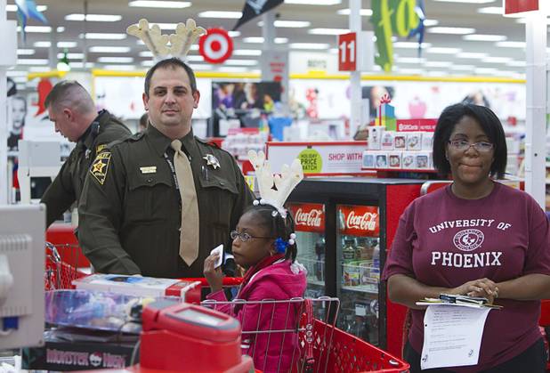 Clark County Deputy Sheriff Bailiff Alberto Coman waits in the checkout line after shopping with Alajah Caddell and her mother Keshia Gray during an annual Shop With A Cop event at the Target store at 2189 W. Craig Rd. in North Las Vegas, Wednesday, December 5, 2012.