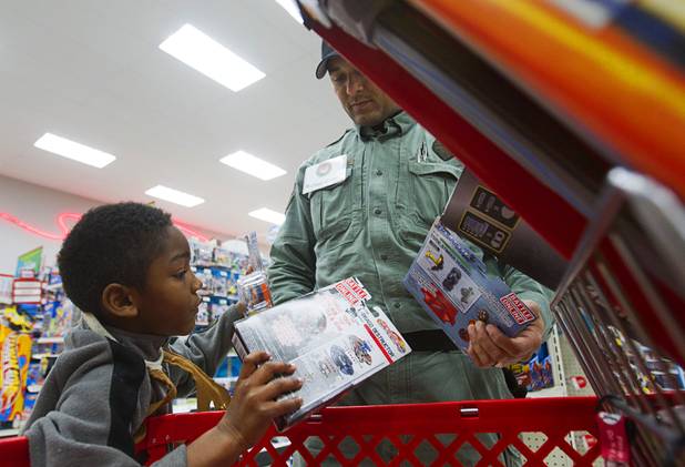 Demar Wingo, 7, makes a decision on what toy to put back after going over budget with North Las Vegas SWAT officer  Michael Graves during an annual Shop With A Cop event at the Target store at 2189 W. Craig Rd. in North Las Vegas, Wednesday, December 5, 2012.