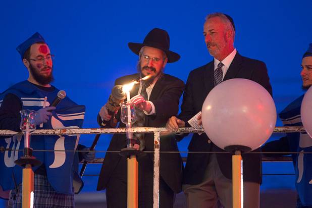 Levi Harlig, left, dressed as dreidel, looks on as his father Rabbi Shea Harlig, center, and Clark County District Attorney Steve Wolfson light a Hanukah menorah during a lightning ceremony at the Fremont Street Experience in downtown Las Vegas Sunday, Dec. 9, 2012.  Chabad of Southern Nevada sponsored the event. The Jewish holiday of Hanukah started Saturday evening and runs though Dec. 16.