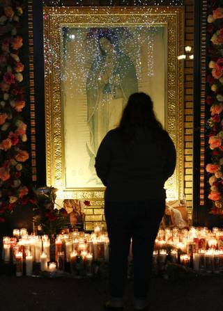 Fan Jenny Guerrero pays tribute to singer Jenni Rivera at a makeshift memorial in front of an image of the Virgin of Guadalupe at the Plaza Mexico shopping center in Lynwood, Calif., early Monday, Dec. 10, 2012. 