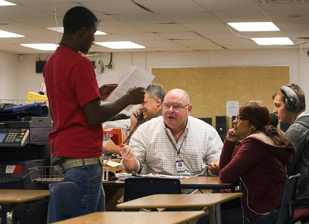 English teacher Roy Addington talks with a student during class ...