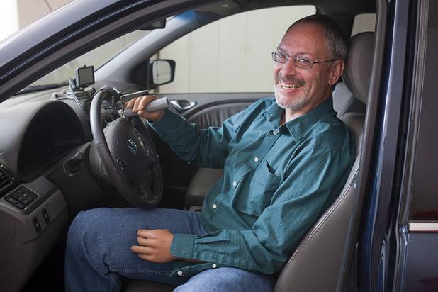Las Vegas resident Scott Martin, who lost his hands and feet due to the flesh eating disease, is shown in his minivan at his home Wednesday, Dec. 12, 2012. Martin created a custom spinner that he uses to help him steer with his prosthetic hands.