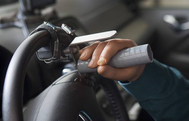 Las Vegas resident Scott Martin, who lost his hands and feet due to the flesh eating disease, displays a custom spinner on the steering wheel of his car Wednesday, Dec. 12, 2012. Martin created the device to help him steer with his prosthetic hands.