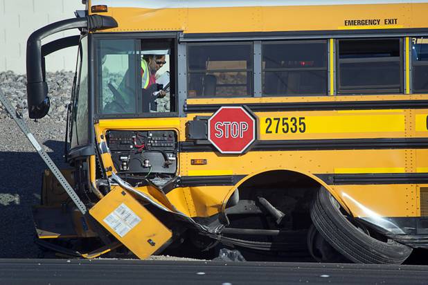 A woman looks over damage to a Clark County School District school bus after an accident with a Honda Accord on Summerlin Parkway westbound near Anasazi Drive Wednesday, Dec. 12, 2012. The Honda was heading eastbound on the parkway when the driver crossed the median and into oncoming traffic, colliding with the bus, Nevada Highway Patrol troopers said.