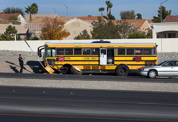A Nevada Highway Patrol trooper takes a photo after an accident involving a Clark County School District school bus and a Honda Accord on Summerlin Parkway westbound near Anasazi Drive Wednesday, Dec. 12, 2012. The Honda was heading eastbound on the parkway when the driver crossed the median and into oncoming traffic, colliding with the bus, troopers said.