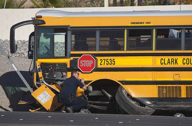 A Nevada Highway Patrol trooper takes a photo after an accident involving a Clark County School District school bus and a Honda Accord on Summerlin Parkway westbound near Anasazi Drive Wednesday, Dec. 12, 2012. The Honda was heading eastbound on the parkway when the driver crossed the median and into oncoming traffic, colliding with the bus, troopers said.
