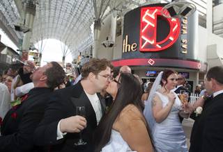 Couples celebrate with champagne at the Fremont Street Experience in downtown Las Vegas Wednesday, Dec. 12, 2012. Ryan Maluka and his bride Danielle Martinez kiss at center. Twelve couples got married at 12:12 pm at the Chapel of the Flowers as part of a KOMP 92.3 radio station promotion. The D Las Vegas put the couples up in newly upgraded rooms, hosted a reception and gave them tickets to 