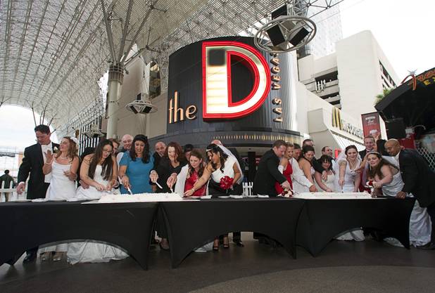 Newlyweds cut cake in front of the D Las Vegas at the Fremont Street Experience Wednesday, Dec. 12, 2012. Twelve couples got married at 12:12 pm at the Chapel of the Flowers as part of a KOMP 92.3 radio station promotion. The D Las Vegas put the couples up in newly upgraded rooms, hosted a reception and gave them tickets to "Marriage Can Be Murder," a comedy, murder-mystery dinner show.