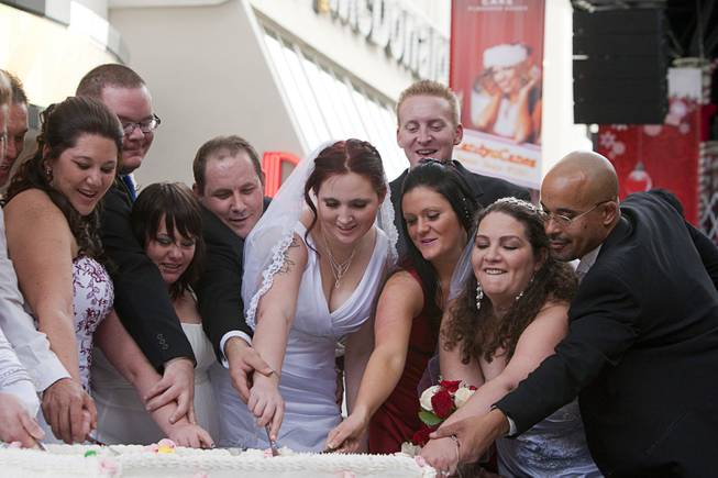 Newlyweds cut cake in front of the D Las Vegas at the Fremont Street Experience Wednesday, Dec. 12, 2012. Twelve couples got married at 12:12 pm at the Chapel of the Flowers as part of a KOMP 92.3 radio station promotion. The D Las Vegas put the couples up in newly upgraded rooms, hosted a reception and gave them tickets to "Marriage Can Be Murder," a comedy, murder-mystery dinner show.