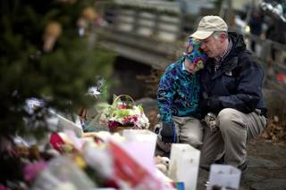 David Freedman, right, kneels with his son Zachary, 9, both of Newtown, Conn., as they visit a sidewalk memorial for the Sandy Hook Elementary School shooting victims, Sunday, Dec. 16, 2012, in Newtown, Conn.