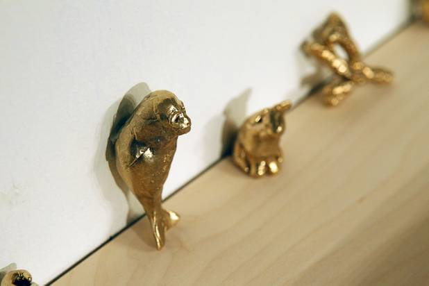 Copies of the original lucky charms are displayed on a wall at the Ellen Harvey Exhibit at the P3 Studio in the Cosmopolitan Monday, Dec. 17, 2012. "Exchange Your Luck" allows guests to swap ineffective lucky charms for new ones.  Two adjacent shelves in P3Studio will hold two sets of 77 different small bronze lucky charms by Ellen Harvey.  Each charm will be an edition of only two. One set of charms will stay in P3Studio for the duration of the residency, while the other set is available for guests to take provided they leave their own lucky charm in exchange. The object for which the charm is swapped will be photographed and its Polaroid installed on the wall.