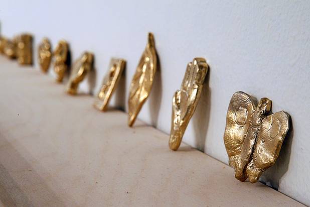Copies of the original lucky charms are displayed on a wall at the Ellen Harvey Exhibit at the P3 Studio in the Cosmopolitan Monday, Dec. 17, 2012. "Exchange Your Luck" allows guests to swap ineffective lucky charms for new ones.  Two adjacent shelves in P3Studio will hold two sets of 77 different small bronze lucky charms by Ellen Harvey.  Each charm will be an edition of only two. One set of charms will stay in P3Studio for the duration of the residency, while the other set is available for guests to take provided they leave their own lucky charm in exchange. The object for which the charm is swapped will be photographed and its Polaroid installed on the wall.