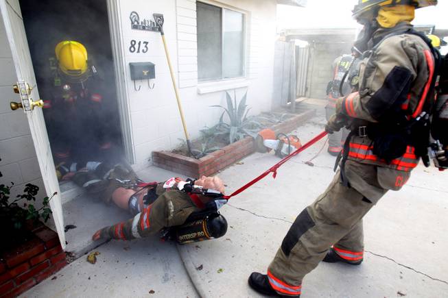 Members of Clark County Fire Department Truck 16  run a search and rescue drill inside a home filled with theatrical smoke near McCarran Airport in Las Vegas on Monday, December 17, 2012.
