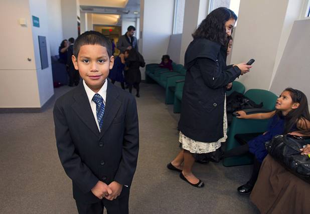Timmy Maciel, 7, poses in a hallway at family court before an adoption proceeding Thursday, Dec. 20, 2012. The family officially adopted four more children, including Timmy, for a total of eleven children.