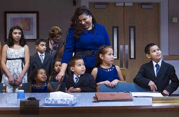 Catlina Maciel stands behind her newly adopted children during an official adoption proceeding at family court Thursday, Dec. 20, 2012. The family officially adopted four more children for a total of eleven children. At the table from left, are Julie, 3, Joey, 5, Sierra, 6, and Timmy, 7.