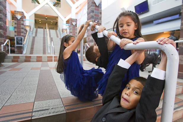 The Maciel children play on a handrail while they wait for paperwork to be filed after an adoption proceeding at family court Thursday, Dec. 20, 2012. The family officially adopted four more children, including Timmy, 7, at bottom right, for a total of eleven children.