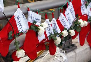 Christmas stockings with the names of shooting victims hang from railing near a makeshift memorial near the town Christmas tree in the Sandy Hook village of Newtown, Conn., Wednesday, Dec. 19, 2012. 