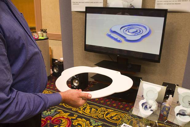 Norman Strohdach holds a prototype of the Catman-Dooty toilet adapter for cats during the annual Cat A Lina Cat Club Championship Cat Show at the Riviera Sunday, Dec. 30, 2012. Strohdach and his wife Viktoria invented the adapter after getting tired of cleaning the litter box. The finished product, shown on the monitor is expected to be available in 6-8 weeks and retail for $69.00. (More information is available at www.catman-doo.com)