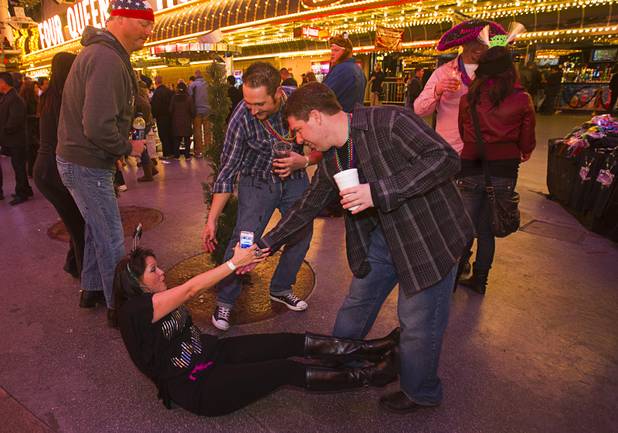 Friends help a woman up after she slipped and fell during the New Years Eve party at the Fremont Street Experience Monday, Dec. 31, 2012.