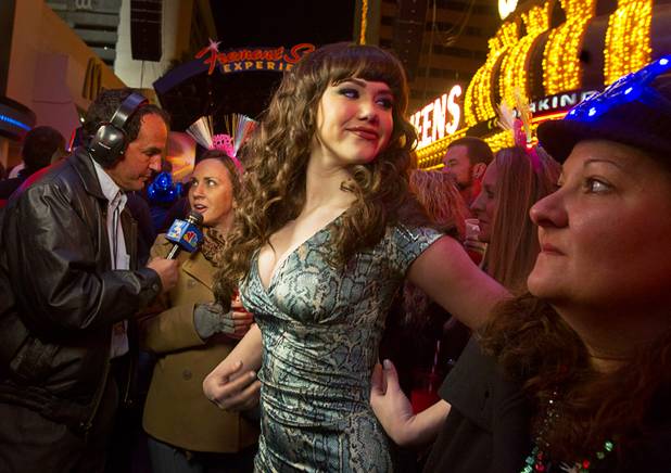 Claire Sinclair, 2011 Playboy Playmate of the Year, waits after an interview with Channel 3-KSNV meteorologist Kevin Janison, left, during the New Years Eve party at the Fremont Street Experience Monday, Dec. 31, 2012.
