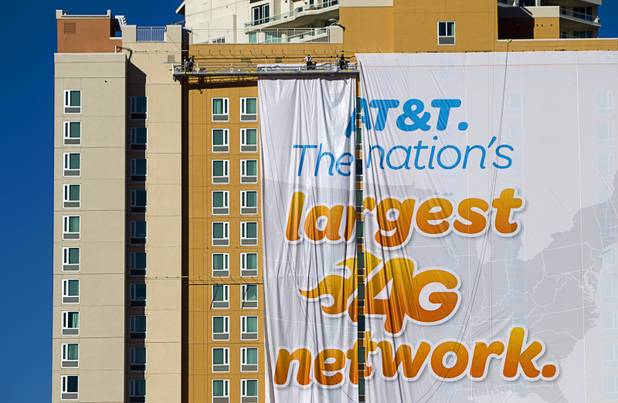 Workers put up a banner advertisement for AT&T on the side of a hotel as they prepare for International CES show in Las Vegas, Nevada January 4, 2013. The annual CES electronics technology trade show is expected to cover 1.85 million square feet of exhibition space and attract 150,000 attendees. The show begins January 8.