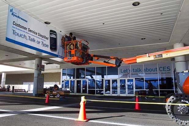 Workers put up an advertisement for Synchronoss at the Las Vegas Convention Center as they prepare for International CES show in Las Vegas, Nevada January 4, 2013. The annual CES electronics technology trade show is expected to cover 1.85 million square feet of exhibition space and attract 150,000 attendees. The show begins January 8.