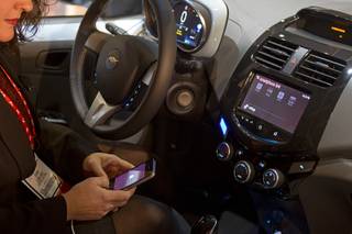 A woman links her iPhone to the MyLink system in a Chevrolet Spark at the opening press event of the 2013 International CES at the Mandalay Bay Convention Center Sunday, January 6, 2013. In addition to being able to run a variety of Apps, the system can also add incorporate Siri, which is a first for an automaker, a representative said.