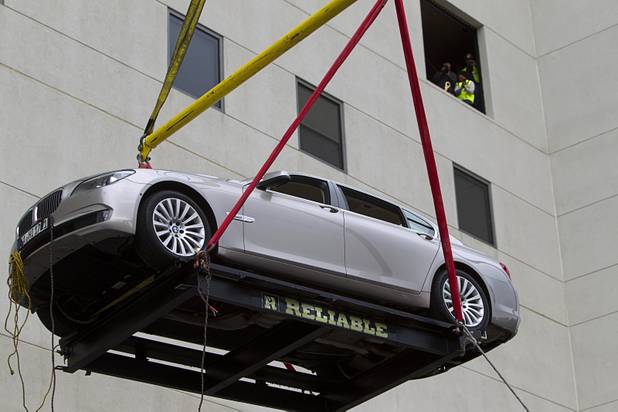 Reliable Crane employees watch from third floor cargo bay as a 2008 BMW 740i, equipped with a new Harman electronic system, is lifted into the Studio at the Palms Sunday, Jan. 6, 2013. The concept vehicle is integrated with new technology which will be unveiled Tuesday, a representative said. Harman is using the recording studio as a showroom to show off the system.