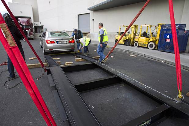 Reliable Crane employees make measurements before lifting a 2008 BMW 740i, equipped with a new Harman electronic system, into the Studio at the Palms Sunday, Jan. 6, 2013. The concept vehicle is integrated with new technology which will be unveiled Tuesday, a representative said. Harman is using the recording studio as a showroom to show off the system.