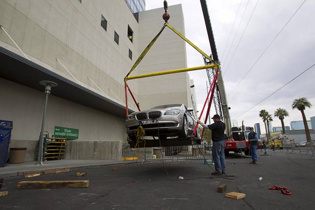 Darell Shaw of Reliable Crane, center, watches as a 2008 BMW 740i, equipped with a new Harman electronic system, is lifted into the Studio at the Palms Sunday, Jan. 6, 2013. The concept vehicle is integrated with new technology which will be unveiled Tuesday, a representative said. Harman is using the recording studio as a showroom to show off the system.