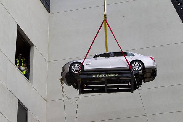 Reliable Crane employees watch from a third floor cargo bay as a 2008 BMW 740i, equipped with a new Harman electronic system, is lifted into the Studio at the Palms Sunday, Jan. 6, 2013. The concept vehicle is integrated with new technology which will be unveiled Tuesday, a representative said. Harman is using the recording studio as a showroom to show off the system.