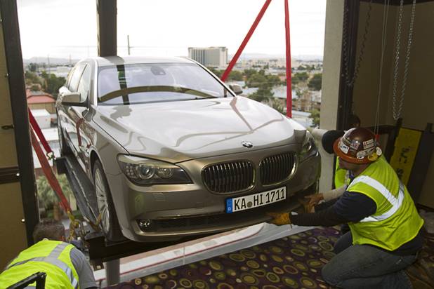 Reliable Crane employees secure a patform to the third floor cargo bay as a 2008 BMW 740i, equipped with a new Harman electronic system, is lifted into the Studio at the Palms Sunday, Jan. 6, 2013. The concept vehicle is integrated with new technology which will be unveiled Tuesday, a representative said. Harman is using the recording studio as a showroom to show off the system.