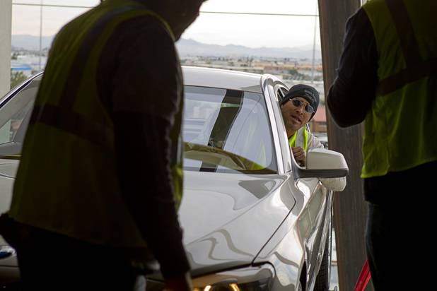 Dave Bell, of Reliable Crane, calls out after realizing that the car is completely out of gas and can not be driven off the platform into the Studio at the Palms Sunday, Jan. 6, 2013. The car was purposely kept low on fuel because it was going into the building. The concept BMW 740i, equipped with a new Harman electronic system, will be unveiled Tuesday, a representative said. Harman is using the recording studio as a showroom to show off the system.