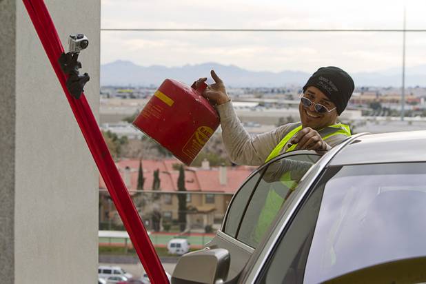 Dave Bell, of Reliable Crane, adds gas to a car being lifted into the Studio at the Palms Sunday, Jan. 6, 2013. The car was purposely kept low on fuel because it was going into the building.The concept BMW 740i, equipped with a new Harman electronic system, will be unveiled Tuesday, a representative said. Harman is using the recording studio as a showroom to show off the system.