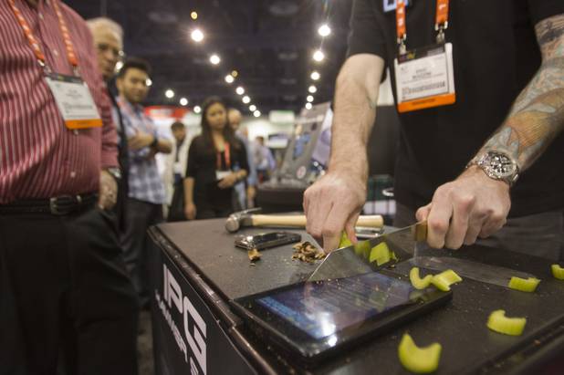 Eric Mazzini slices celery on top of a Kindle protected with an Invisible Phone Guard (IPG) covering during the first day of the 2013 International CES in the Las Vegas Convention Center Tuesday, Jan. 8, 2013. The company makes the scratch-proof, self-healing protective covers for over 600 devices. Prices range from $12.95 to $24.95 depending on the model. STEVE MARCUS