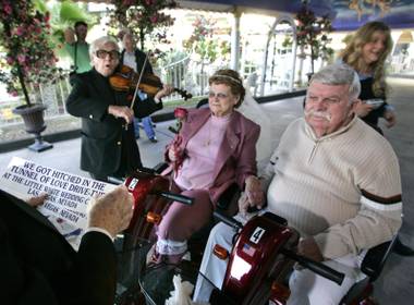 Sasha Semenoff plays a violin for Margaret Nixon, 73, and Francis Murphy, 75, of Defiance, Ohio kiss during their wedding in the “Tunnel of Love” drive-though at the Little White Wedding Chapel Monday, December 5, 2005.  