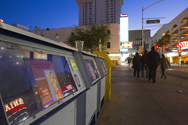 A family passes news racks advertising adult "entertainers" in downtown Las Vegas, Sunday, Jan. 20, 2013.