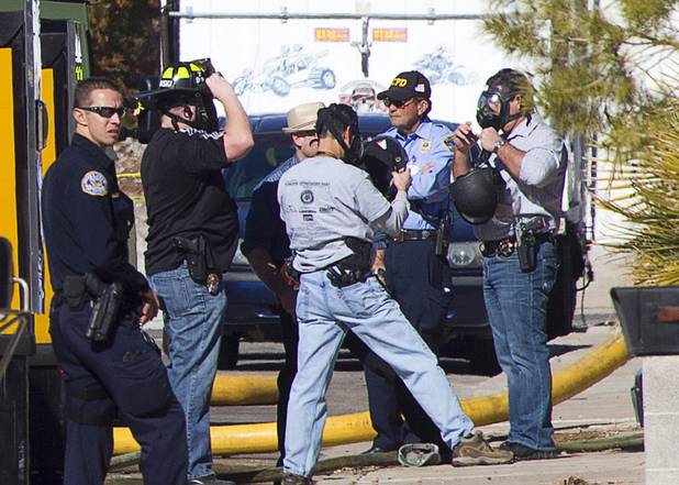 Law enforcement officials put on protective masks before entering a house as they investigate a shooting and fire in Boulder City Monday, Jan. 21, 2013. 