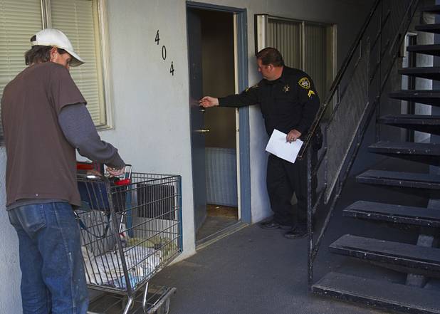 Deputy Constable Patrick Geary prepares to enter an apartment near Karen Avenue and Joe W. Brown Drive Tuesday, Jan. 22, 2013. Maintenance man Mark Weaver waits to change the lock.