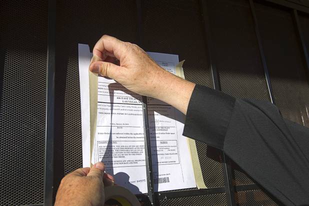 Deputy Constable Patrick Geary tapes a 24-hour eviction notice on the door of an apartment  in the southwest part of the Las Vegas Valley Tuesday, Jan. 22, 2013. Apartment managers can post the notice themselves but often hire a constable for an official posting so they have evidence in case the eviction is contested in court, he said.