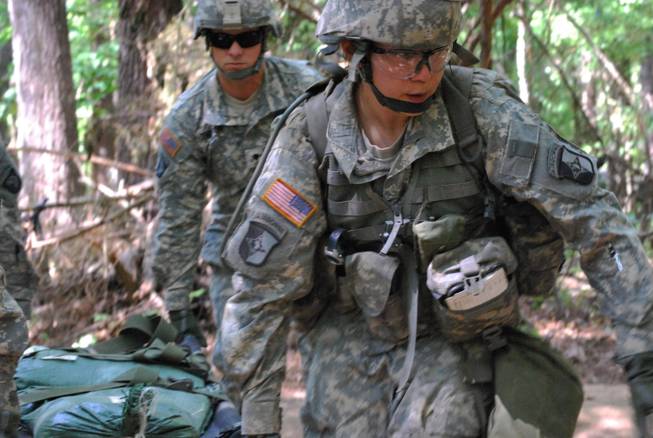 In a May 9, 2012, file photo, Capt. Sara Rodriguez, 26, of the 101st Airborne Division, carries a litter of sandbags during the Expert Field Medical Badge training at Fort Campbell, Ky.