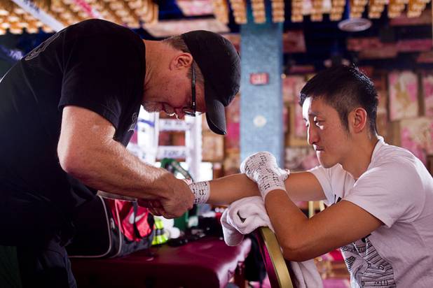 Trainer Freddie Roach (L) wraps the hands of Chinese light flyweight boxer Zou Shiming before a workout in a training facility at the Palazzo in Las Vegas, Nevada February 8, 2013. Zou, a two-time Olympic gold medalist and three-time world amateur champion, will make his professional debut April 6 at the Venetian Macao Resort in Macau.
