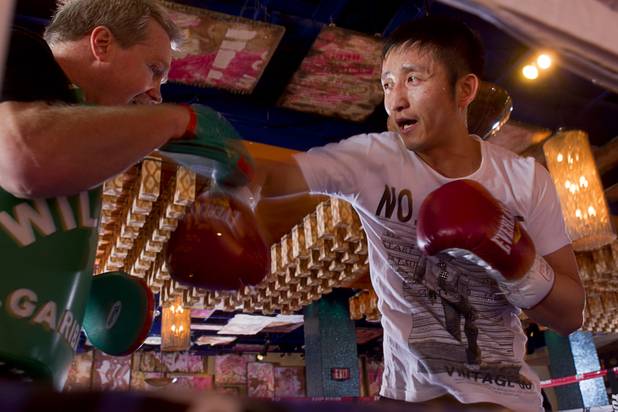 Chinese light flyweight boxer Zou Shiming (R) works on his timing with trainer Freddie Roach during a workout in a training facility at the Palazzo in Las Vegas, Nevada February 8, 2013. Zou, a two-time Olympic gold medalist and three-time world amateur champion, will make his professional debut April 6 at the Venetian Macao Resort in Macau.